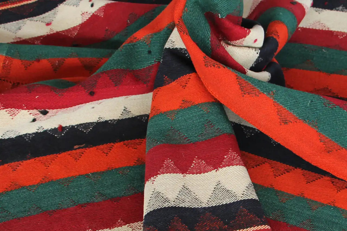 Jajim rug fabric detail with crossed stripes in red, green, orange, and cream.