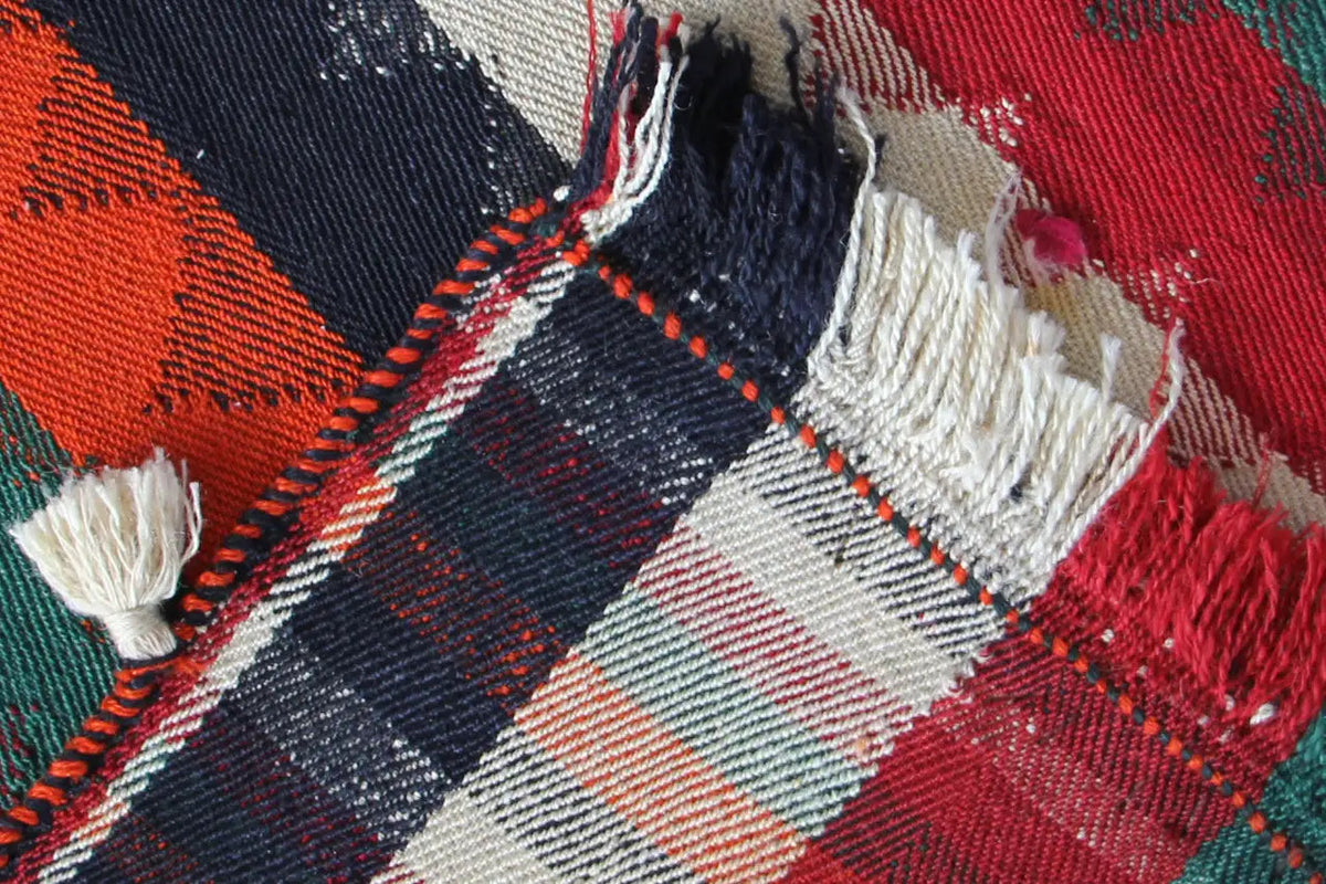 Jajim rug detail: checked pattern in dark blue, red and cream, with tassels.