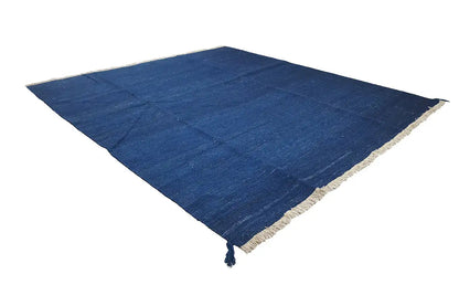 Blue kilim rug laid diagonally, with a beige border and fringes