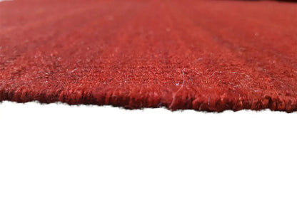 Close-up of the edge of the red Simple kilim rug with short pile and a frayed edge