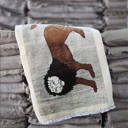 Gabbeh rug with a lion motif, draped over a blanket; beige background, brown animal