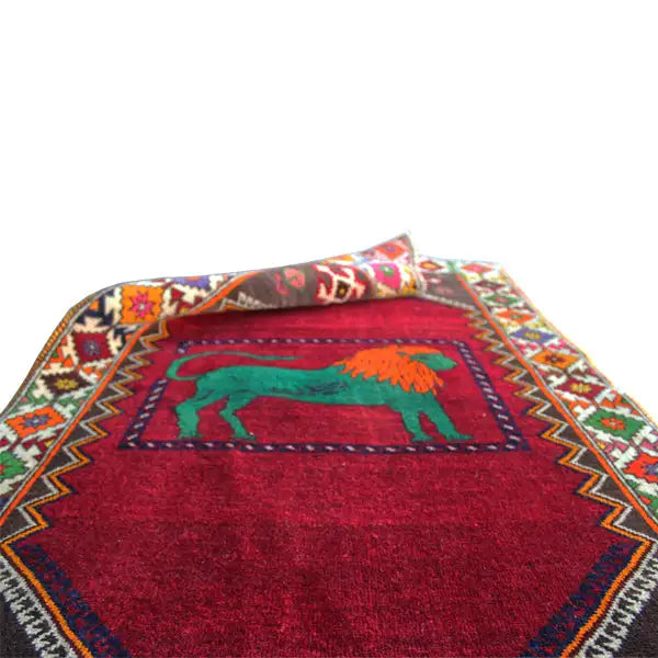Gabbeh rug with a red background and green lion motif, multicolored border
