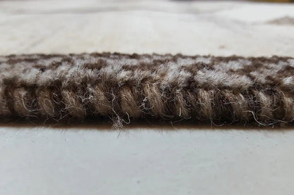 Close-up of the carpet edge: short, dense pile in dark brown on a light background