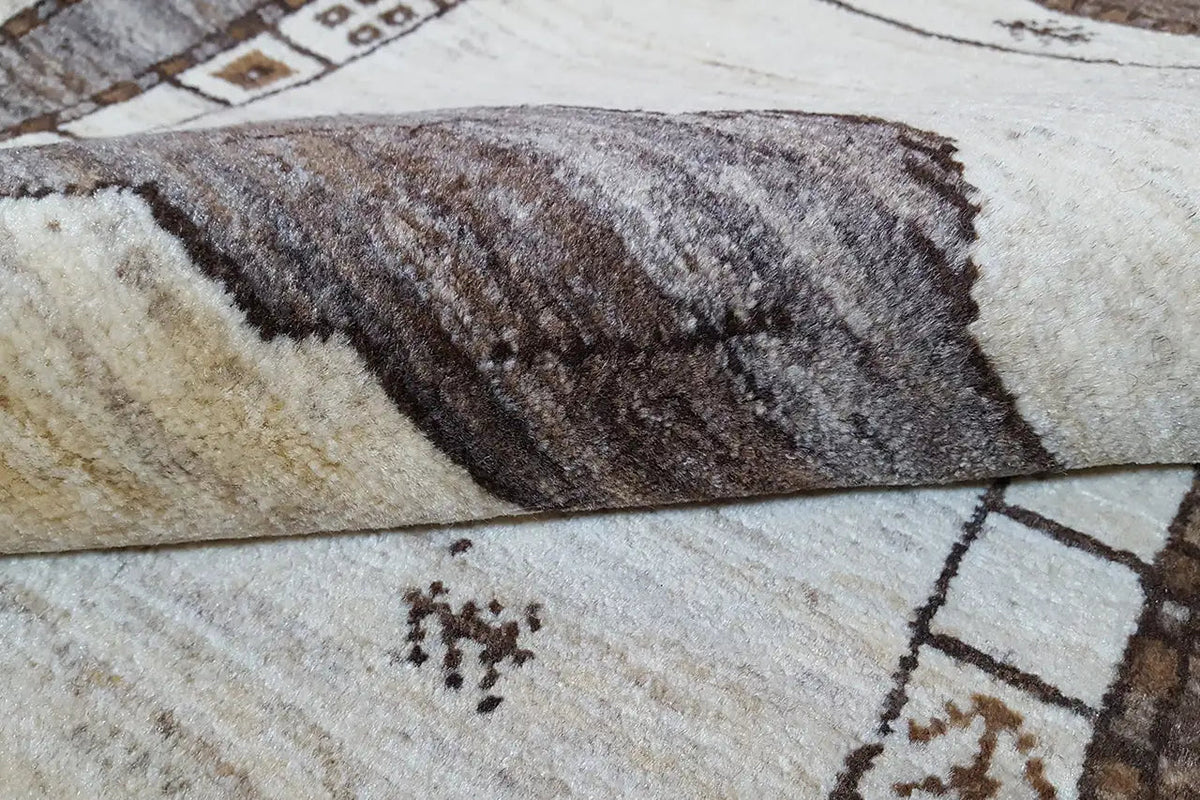 Gabbeh rug in detail: high-pile woven texture, brown pattern on a light background