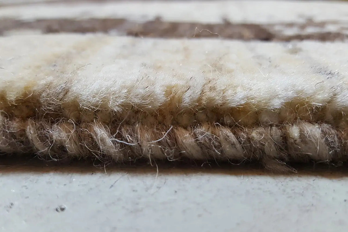 Carpet fringe along the edge, dense pile in light beige with brown areas