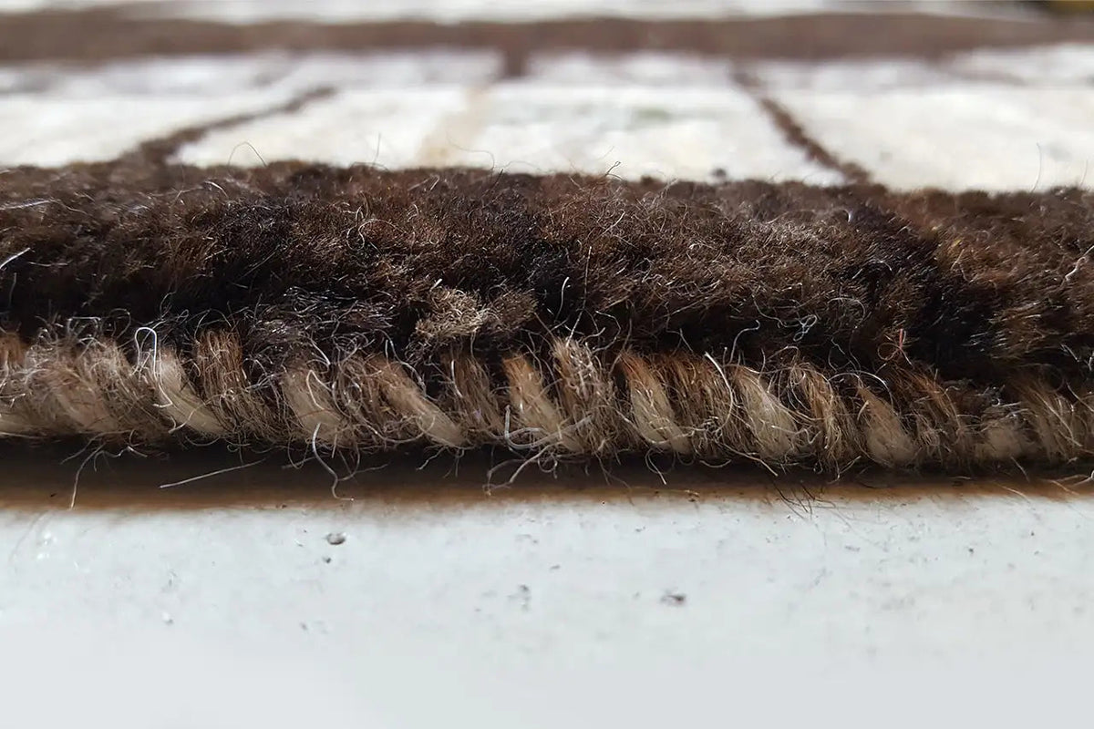 Close-up of the carpet edge with dense pile in brown and beige tones