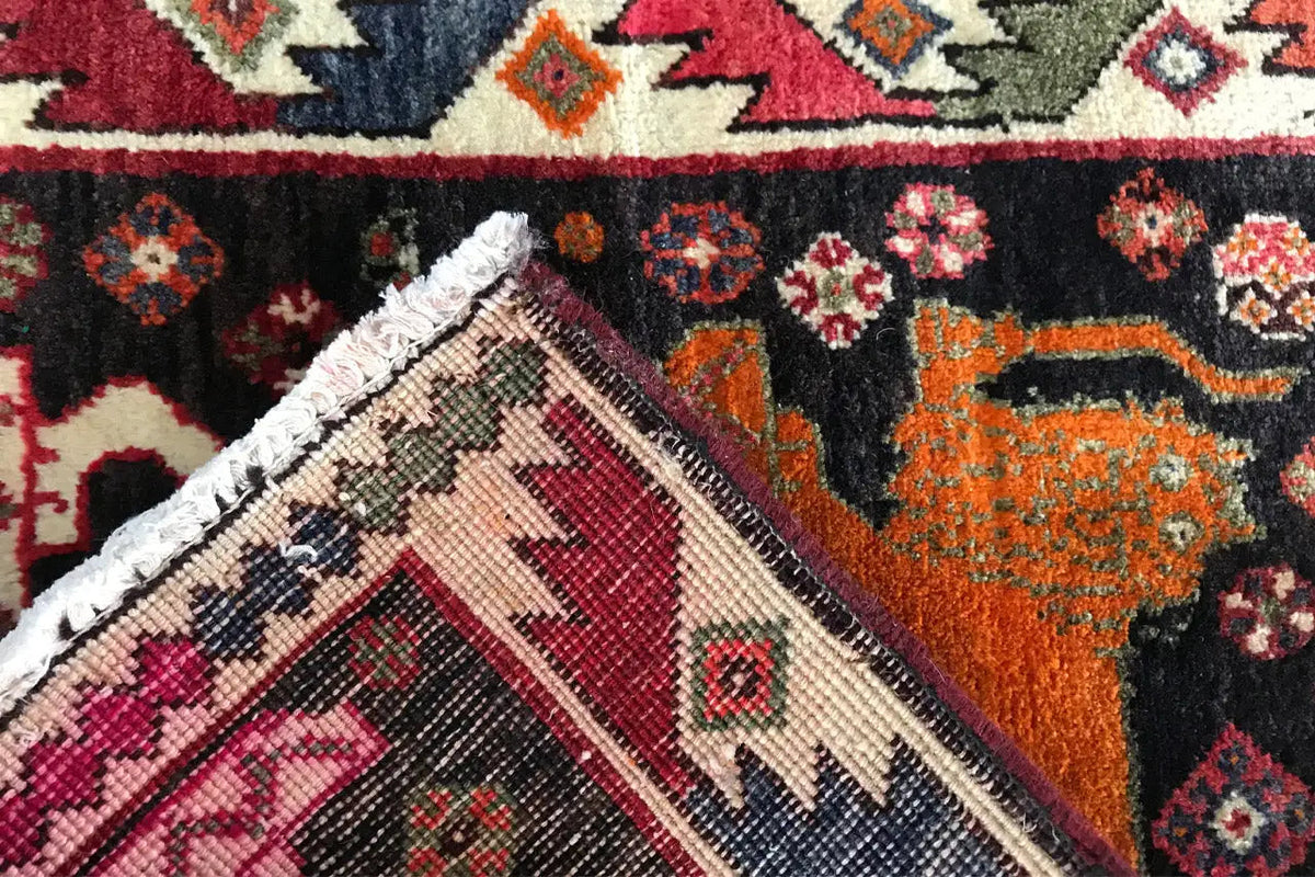 Carpet Poschti Qashqai close-up: orange-black field with animal and diamond patterns