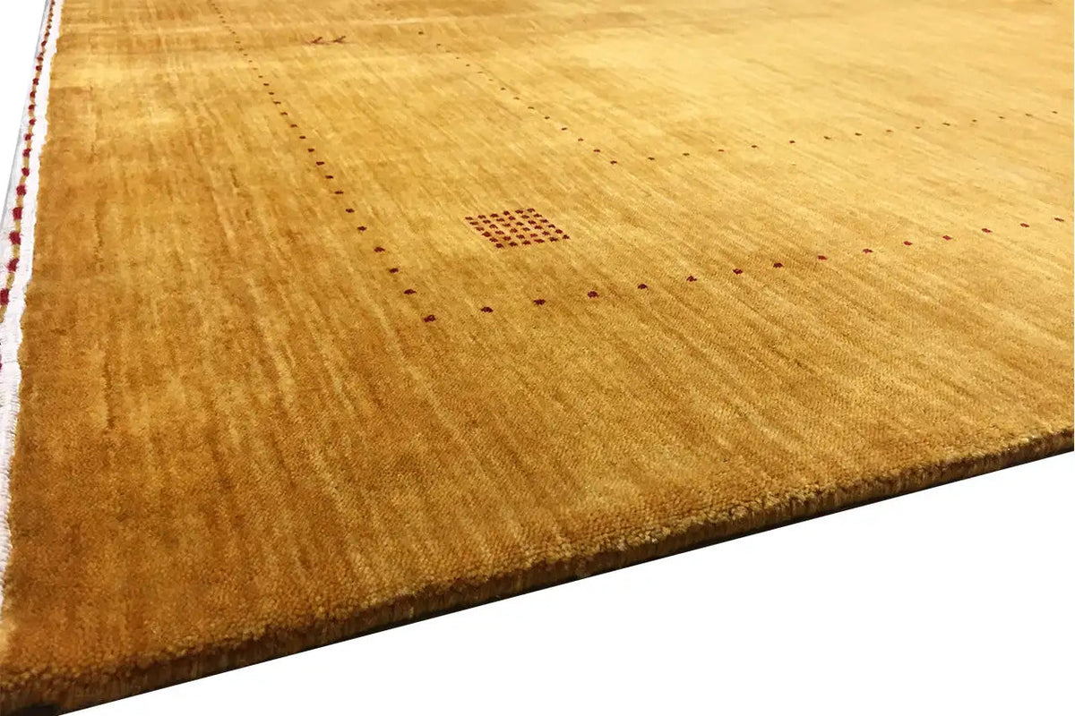 Ochre-colored Gabbeh rug with small square patterns and fine lines, angled view