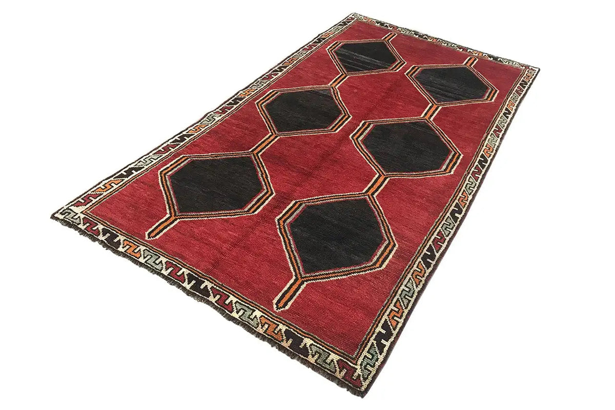 Red Lori rug with a black hexagon pattern and decorative border