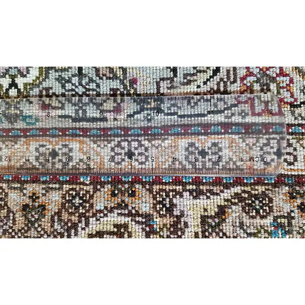 Close-up of the carpet pile with a dense pattern and colorful threads in brown, blue, and green