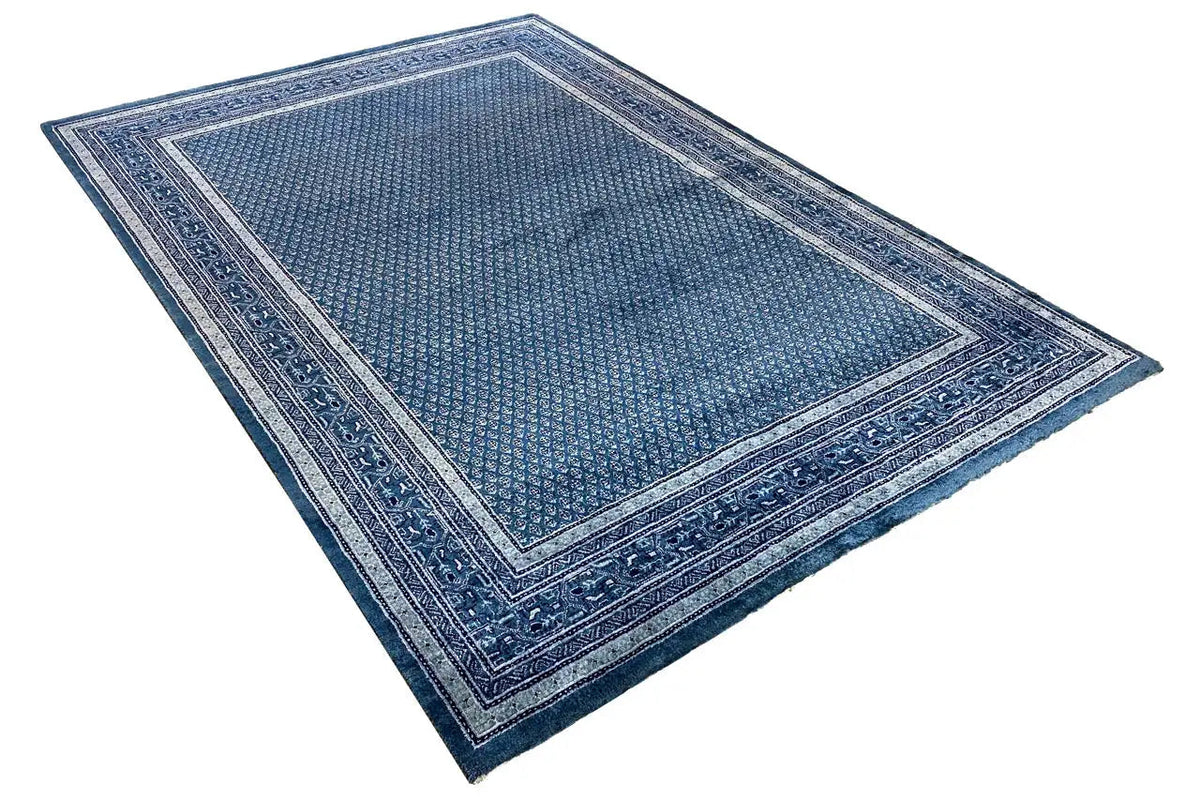 Blue rectangular rug with a centered pattern and decorative border design