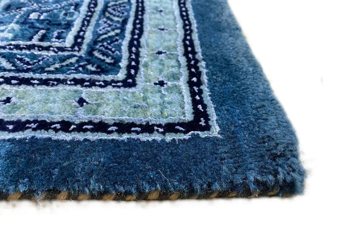 Close-up of the carpet edge with fringes and a blue woven pattern
