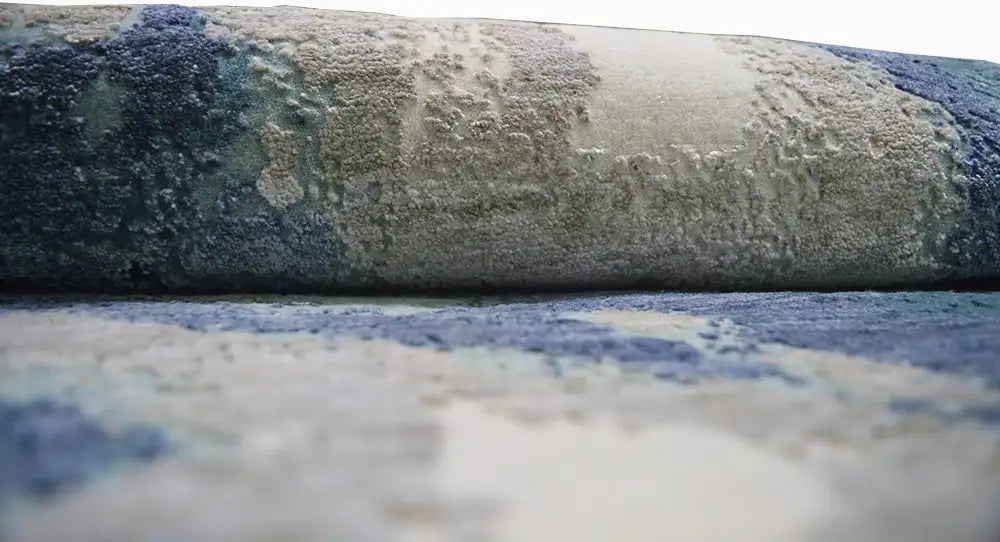 Detail of the round designer rug: aged look, blue and beige tones in the pattern.