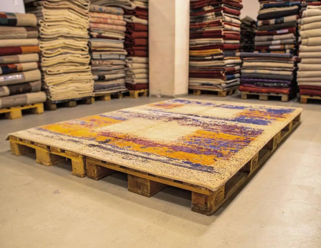 Designer rug on a pallet with an abstract pattern in blue, purple, and orange on a light background
