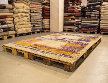 Designer rug on a pallet with an abstract pattern in blue, purple, and orange on a light background