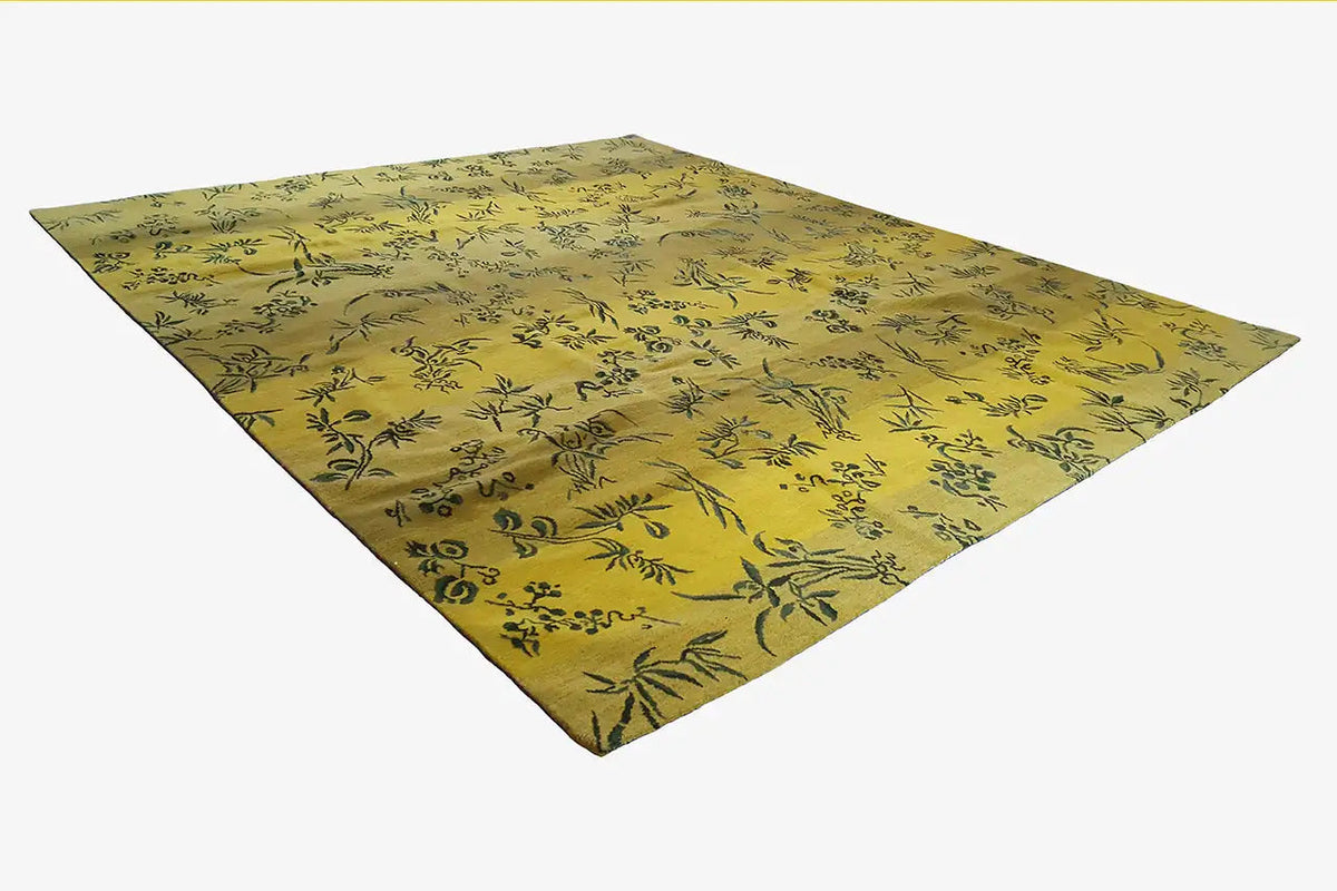 Designer rug in yellow with a dark leaf pattern, square view