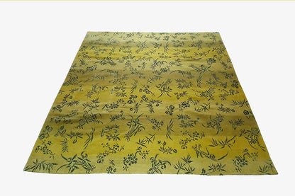Designer rug, yellow, with a delicate leaf and vine pattern and a visible border edge