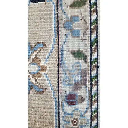 Close-up of a carpet edge with a woven border; blue-and-white ornaments on a light background
