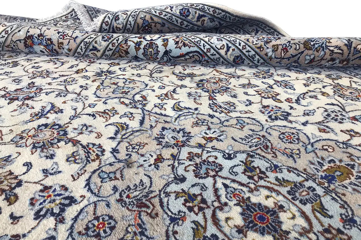 Beige oriental rug with a blue ornamental field, rolled up and with visible creases