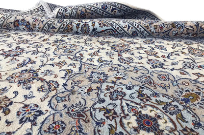 Beige oriental rug with a blue ornamental field, rolled up and with visible creases