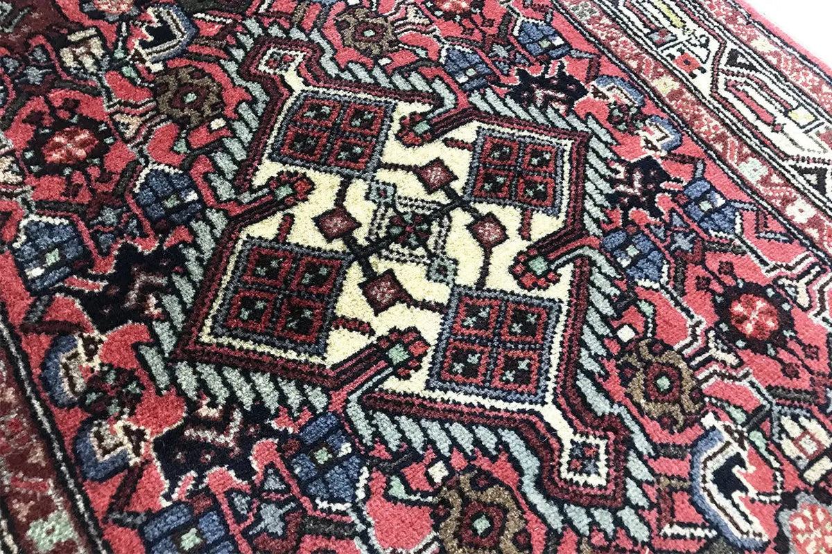 Close-up of a Hamadan rug: red and dark blue ornament, light contrasting lines and borders