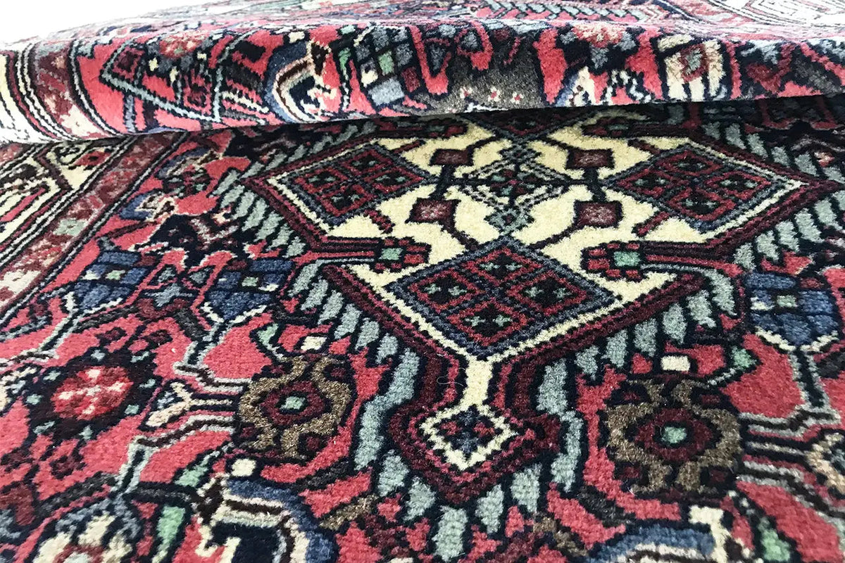 Hamadan carpet detail: bold red ornaments with dark blue, light stars in the inner field