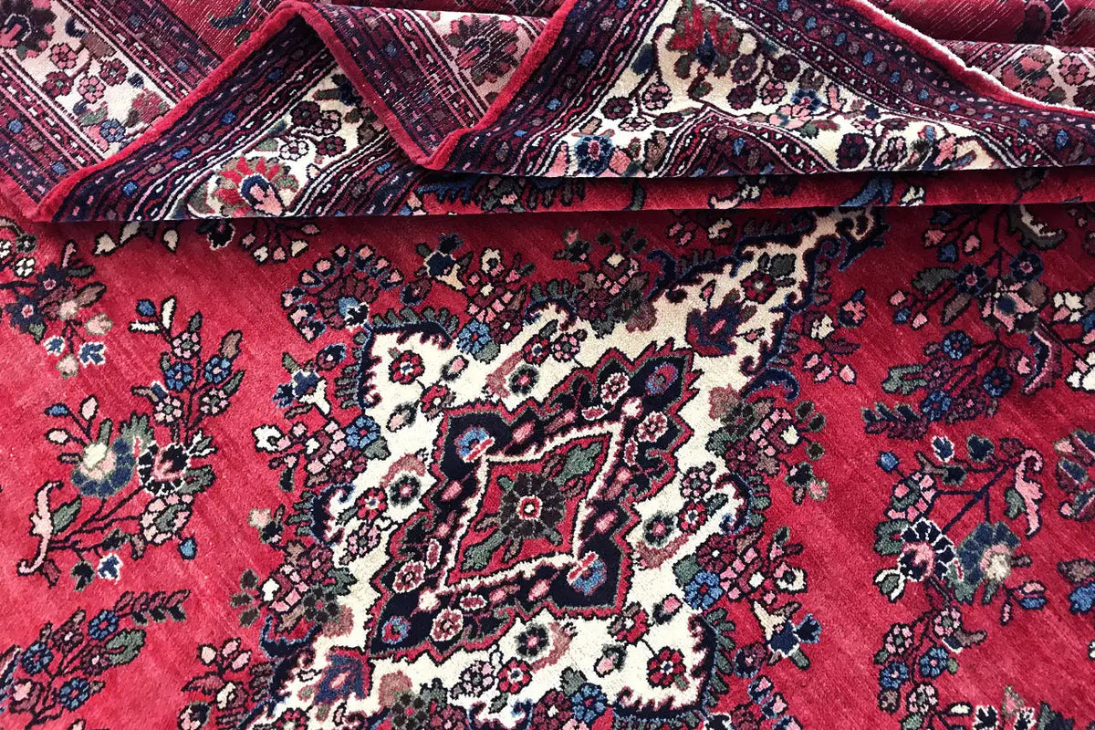 Hamadan rug detail with rolled edge: red field, white-and-blue medallion