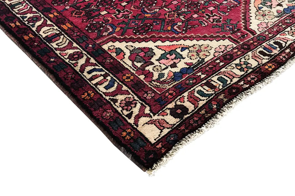 Hamadan runner corner with red background, white partial ornament, and dark-framed border