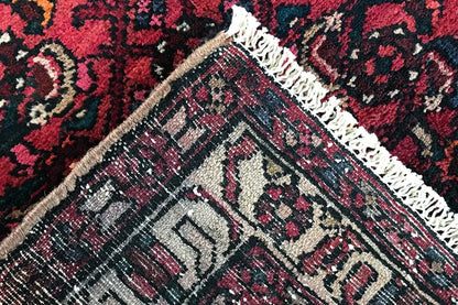 Close-up of the edge: red pattern with a green tinge, light-colored border, and fringes