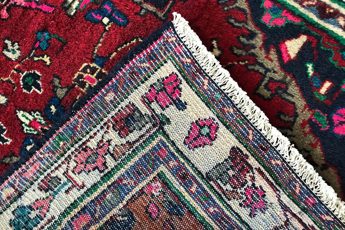 Hamadan runner edge detail with fringes, multicolored cassette motifs on a red background