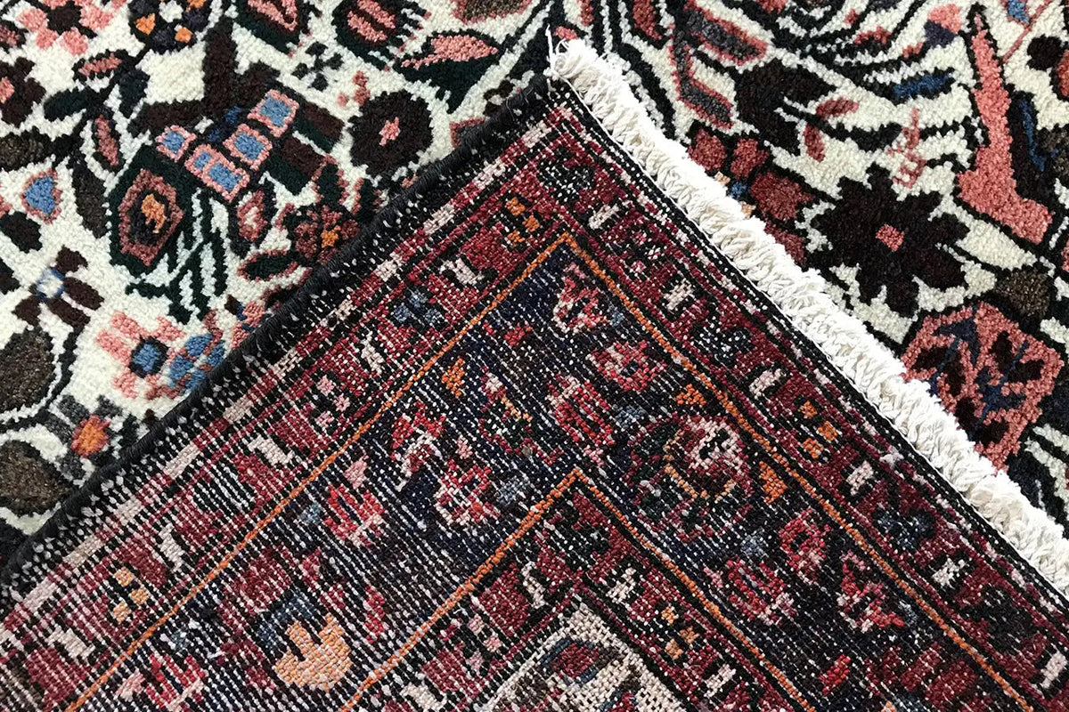 Close-up: carpet runner with a dark central field, red patterned band, and textile texture