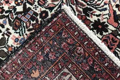 Close-up: carpet runner with a dark central field, red patterned band, and textile texture