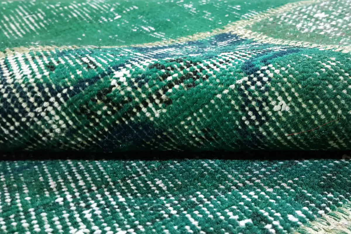 Close-up of the patchwork rug: green texture with a dense, patterned weave.