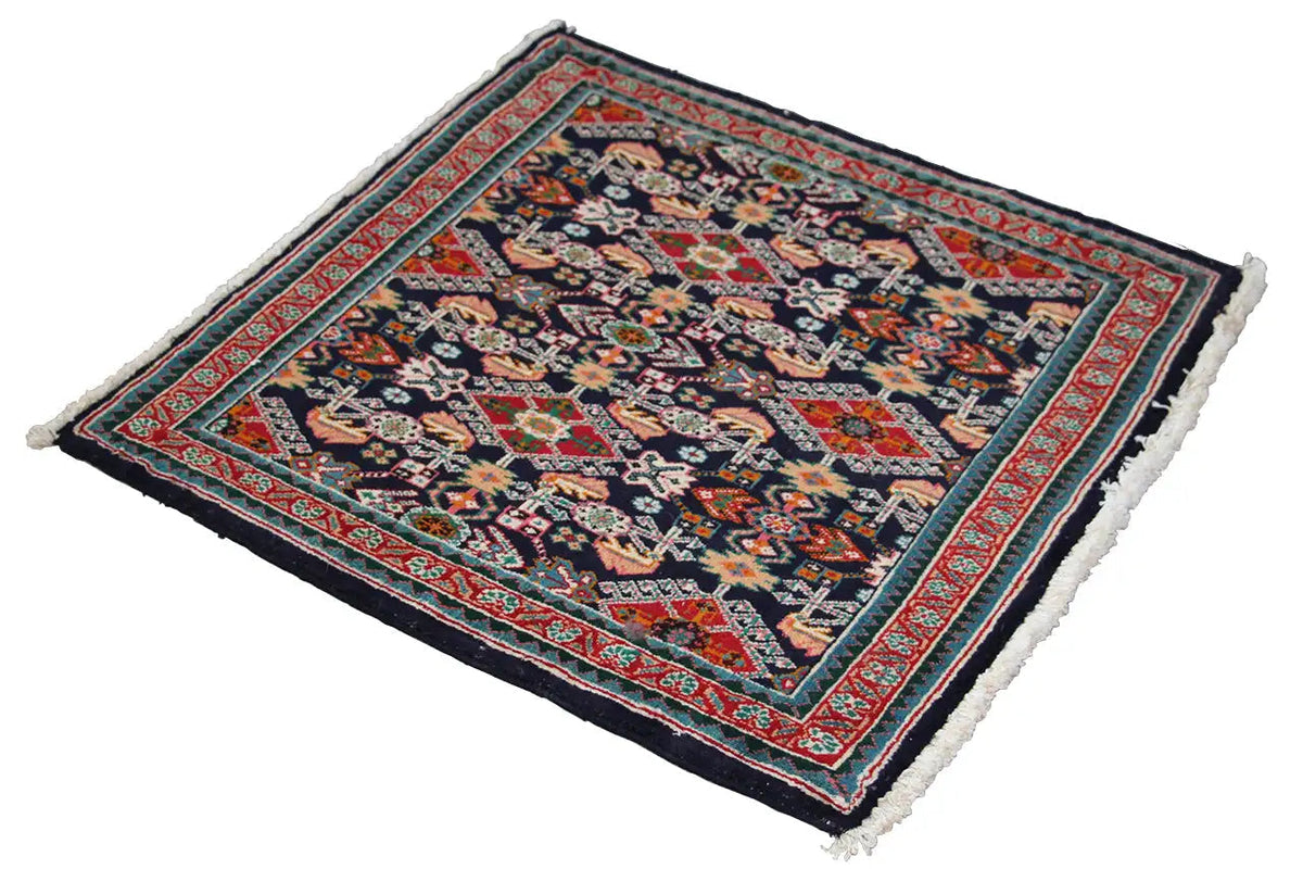 Oriental rug with a dark blue pattern, red border, and white fringe