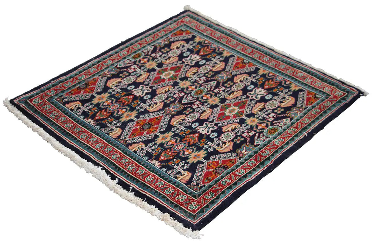 Oriental rug at an angle, dark blue ornamental pattern with a red border and fringes