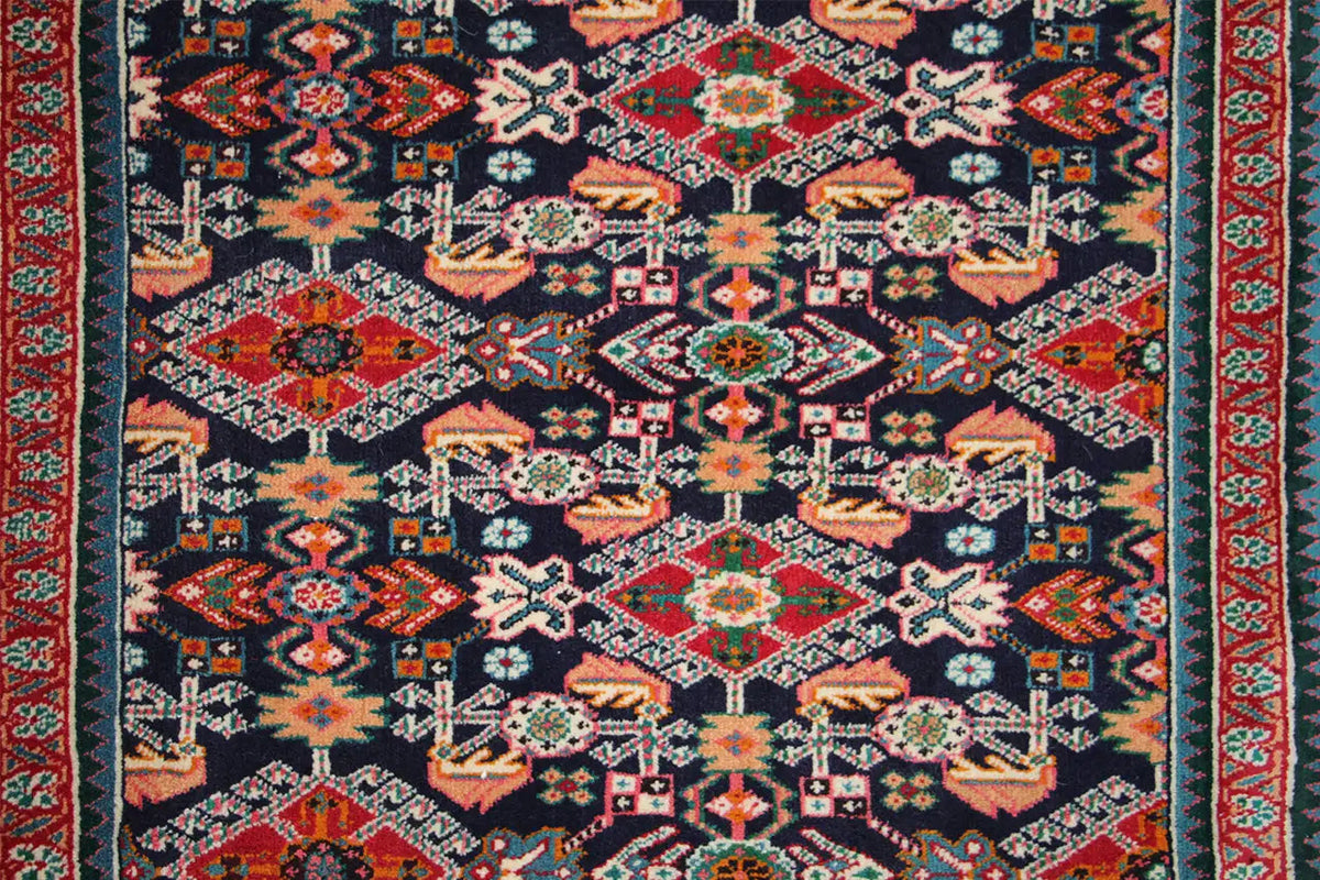 Close-up: dark blue carpet pattern with red accents and multicolored ornaments