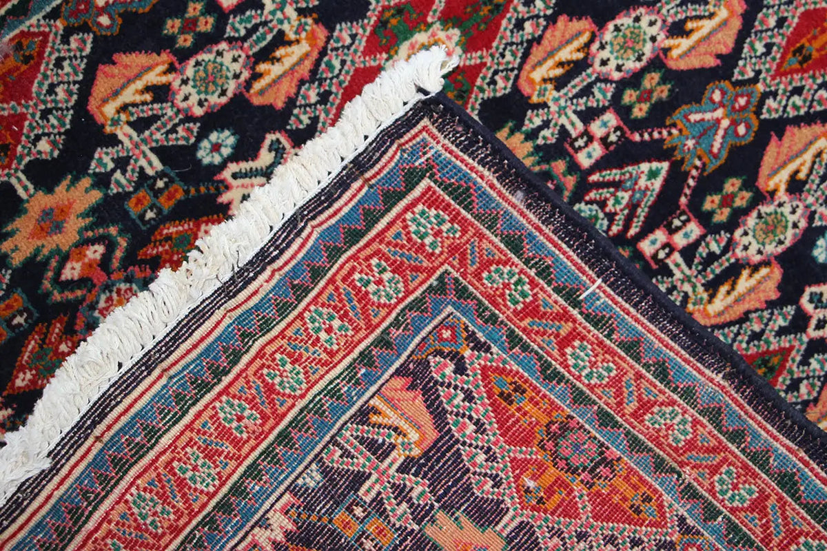 Carpet corner with a dark blue background, red decorative border, and white fringes