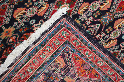 Carpet corner with a dark blue background, red decorative border, and white fringes