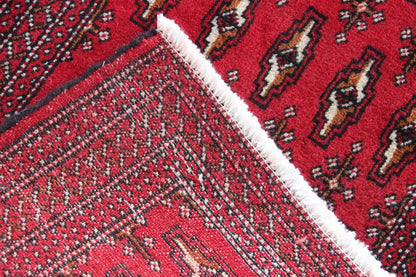 Poshti Turkmen carpet: diagonal detail, red ornaments, white fringes