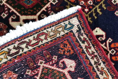 Carpet corner in detail: dark blue pile with a red border and embroidered pattern