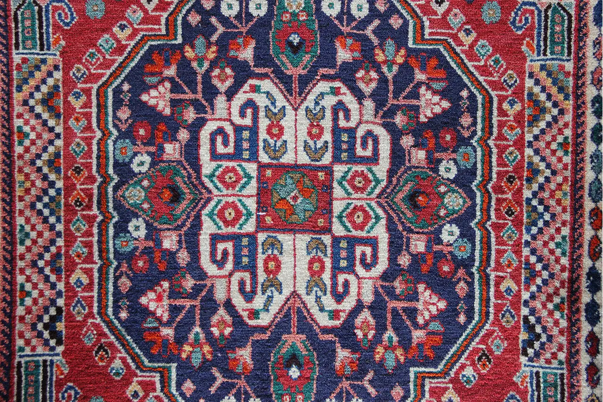 Close-up of the oriental rug’s center with a blue-red ornamental medallion and decorative borders