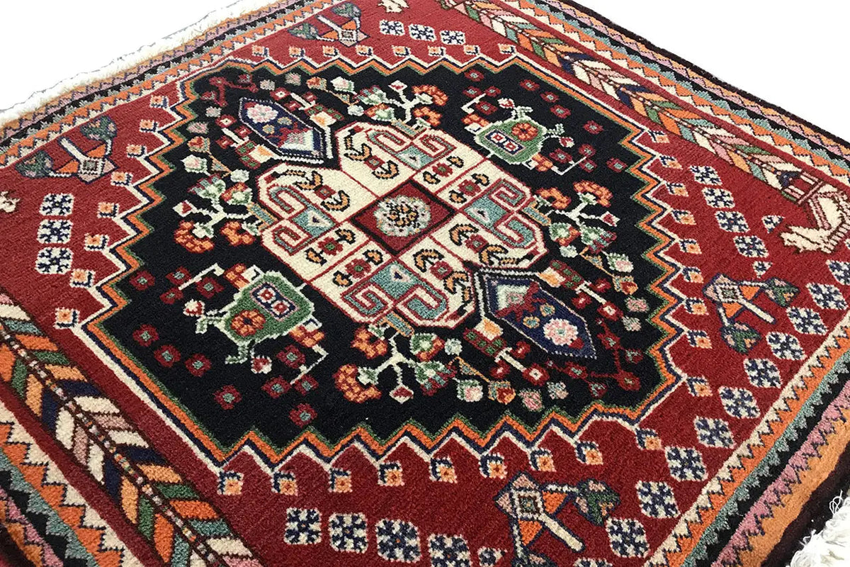 Close-up of an Oriental rug: black center with ornaments, burgundy border and zigzag pattern