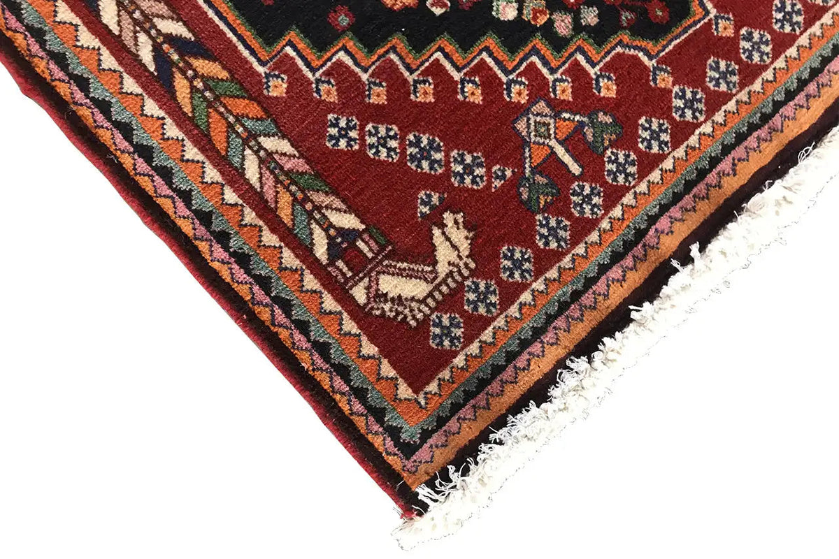 Corner of an Oriental rug with a burgundy field, multicolored border detail, and fringe