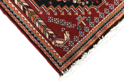 Corner of an Oriental rug with a burgundy field, multicolored border detail, and fringe
