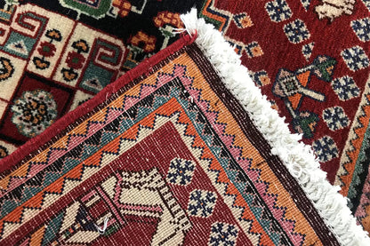 Detail at the edge: fringed selvedge, burgundy border, black field, and colorful ornamentation