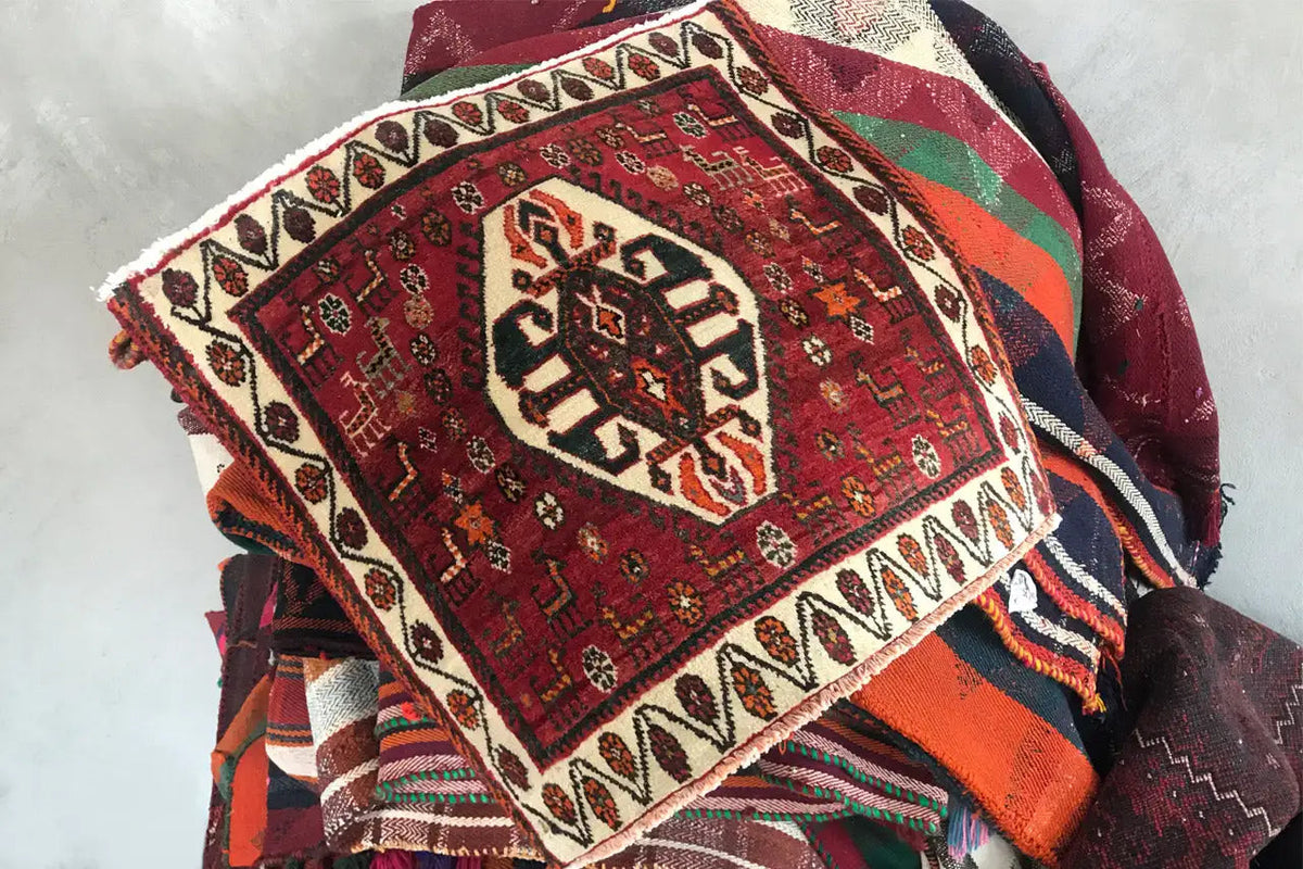 Rug with a red pattern and white border, folded with visible fringe