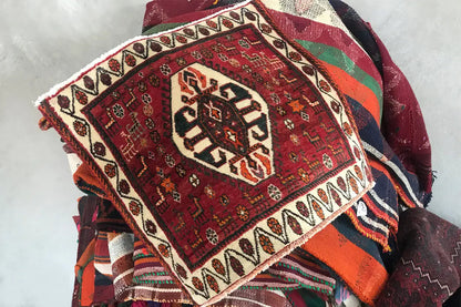 Rug with a red pattern and white border, folded with visible fringe