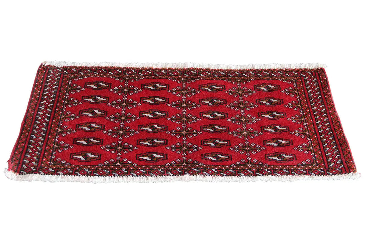 Turkmen carpet, red with dark blue patterns and fringes along the long edge
