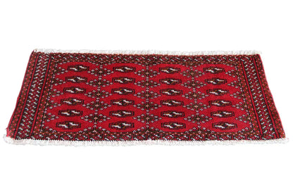 Turkmen carpet, red with dark blue patterns and fringes along the long edge