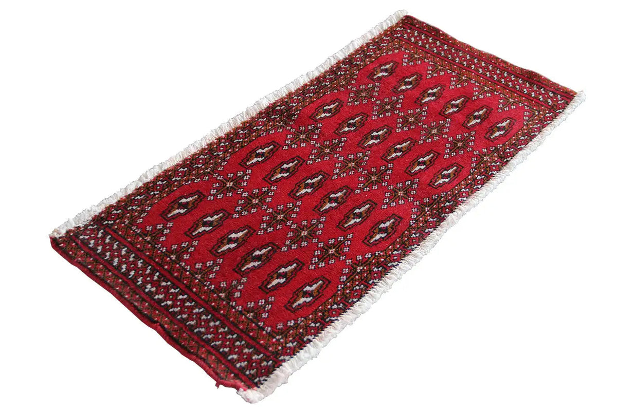 Turkmen carpet laid flat, red design with fine geometric patterns and fringes